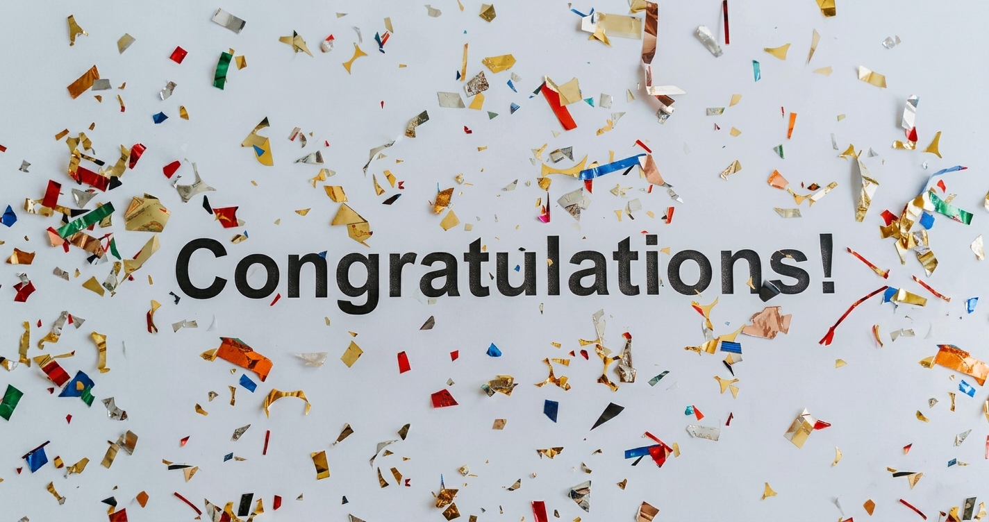 Gold and colorful confetti on a white surface with the word Congratulations written in the center.